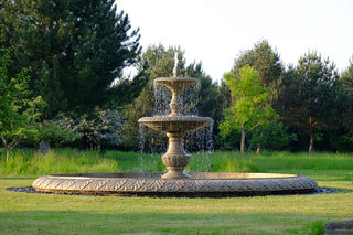 double tier marble fountain in a lush green garden