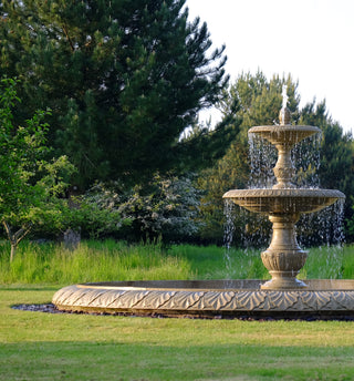 Image of a double tier marble fountain in a lush green garden