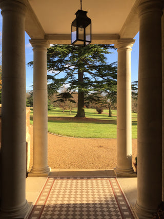 Looking out through a portico over a bright and sunny garden