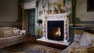 The image depicts a lavishly decorated living room with an ornate marble fireplace, plush sofas, hardwood floors, and blue paneled doors, exuding an air of opulence and classical grandeur.