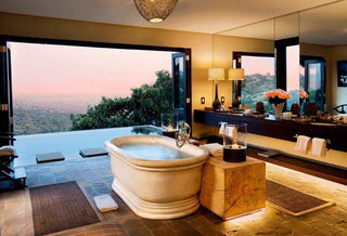 a hand carved marble bathtub with views out over a swimming pool and vast african landscape