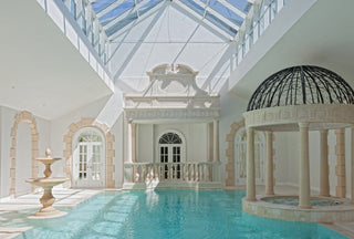 a luxurious indoor swimming pool with marble portico and fountain