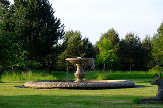 single tier marble fireplace in a lush green garden