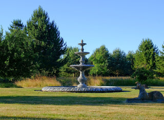 triple tier marble fountain in a lush green garden