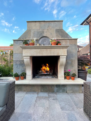 outdoor hand carved stone fireplace with a fire burning inside